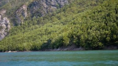 Arnavutluk 'un Koman Gölü' nün sakin sularıyla yemyeşil ormanlar buluşuyor. Bu huzurlu manzara huzurlu bir kaçış sunuyor..
