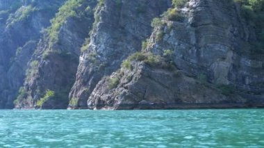 Koman Gölü 'nün sakin turkuaz suları kayalık, ağaçlarla kaplı bir kıyıya yaslanır. Bu huzurlu Arnavut manzarası huzurlu bir kaçış sunuyor.