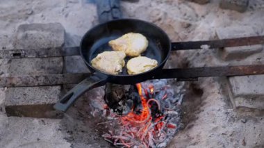 Üç parça baharatlı tavuk göğsü bir kamp ateşinde kızartılıyor, açık hava yemekleri ve basit zevkleri çağrıştırıyor. Kırsal bir hayatta kalma sahnesi, kendi kendine yetme, ya da sakin bir kamp.
