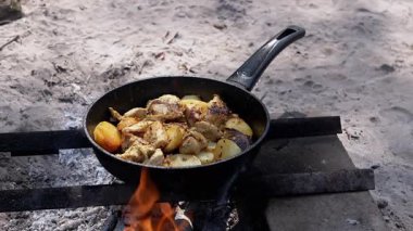 Tavuk ve patates bir kamp ateşinde tavada kızartılır. Lezzetli kamp yemekleri. Açık hava yemekleri..