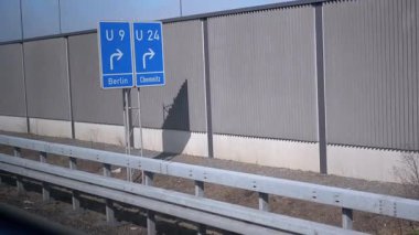 Arka planda gürültü bariyeri olan Berlin ve Chemnitz 'e giden yolu gösteren yol işaretleri. Seyahat, navigasyon ve Almanca yol ağı videoları için kullanışlı.