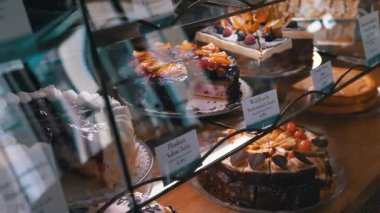 Dekorasyon ve dokuların detaylarını vurgulayarak, bir kafe vitrinindeki pastaların yakın plan görüntüsü. Yemek blogcuları ve mutfak içeriği için ideal.