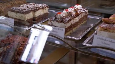 Almanca etiketli lezzetli kekler bir fırın vitrininde oturur, Alman şekerlemelerine göz atmayı teklif ederler..