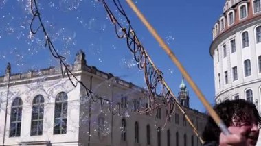 Dresden, Almanya - 11 Nisan 2025: Sabun köpükleri, tarihi Alman mimarisi ve mavi gökyüzü ile Dresden meydanında yüzer ve sürüklenir. Yolculuk ve keyifli anlar için harika.