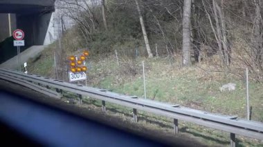 Turuncu uyarı ışıkları ve otoyol altgeçidinin yanında 7-19 saat sınırlama işaretini geçen bir kamyon. Ulaşım, güvenlik ve altyapı projeleri için ideal.