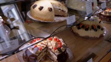 Pastalar bir kafe vitrininde özenle düzenlenir ve cazip bir seçim sunulur. Aşçılık videoları ve tanıtım materyalleri için ideal.
