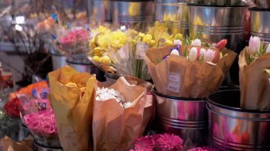 Kağıda sarılı çeşitli çiçek buketlerinin yakın plan görüntüsü, bir çiçekçide satılmaya hazır. Çiçekçi, market ve bahar temaları için ideal.