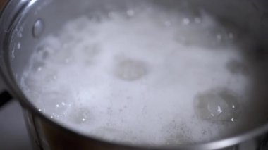 Yüzeyinde yoğun bir köpük tabakası oluşturan bir tencerede kaynayan suyun yakın plan görüntüsü. Yemek pişirme ve yemek hazırlama videoları için ideal.