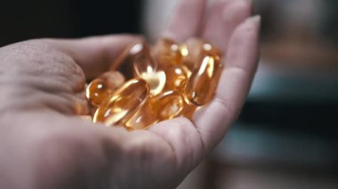 Bir el, sağlıklı bir yaşam tarzındaki rollerini vurgulayan altın balık yağı kapsüllerinden oluşan bir koleksiyon tutuyor. Takviye ve refah için harika..