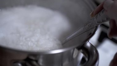 Bir kaşık kepçesi tencerede pilav pişirdi. Pirinç beyaz ve yumuşaktır. Yemek ve yemek videoları için ideal..