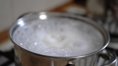 Fırının üstünde paslanmaz çelik bir tencerede kaynar su kabarcıkları ve girdaplar. Yemek ve yemek hazırlama sahneleri için ideal..