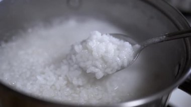 Pirinç lapası metal bir tavada pişirilir. Kaşıkla, lapanın hazır olup olmadığını kontrol et. Sağlıklı yemek pişirmek..