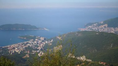 Karadağ 'ın Budva kentinin Adriyatik kıyısındaki manzarası. Yeşillik, şehir manzarasını ve St. Nicholas Adası 'nı süslüyor. Huzuru ve Akdeniz 'in güzelliğini çağrıştırıyor.