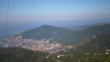 Budva şehri, ön planda elektrik hatlarının doğal manzaraya bir miktar şehir kontrastı eklediği yüksek bir bakış açısından görülüyor..