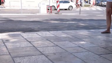Hırvatistan, Dubrovnik - Ağustos 2024: Güneşli bir günde insanlar şehir kaldırımında yürüyor. Bu canlı sahne şehir seyahatini, turizmi ve günlük hayatı temsil ediyor..
