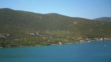 Midye çiftlikleri ve yemyeşil dağların arasına yerleşmiş güzel kıyı köyleriyle sakin bir körfez. Güneşli bir günde sakin bir deniz manzarası. Su ürünleri ve kıyı yaşamı.