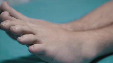 Turkuaz bir yüzeyde dinlenen bir adamın bacakları, sağlık, rahatlama ve vücut bakımı projeleri için uygundur..