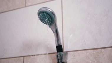 Paslı, kirli bir banyo musluğundan fayanslı bir duvara su dökülüyor. Sahne, bakım ve onarım ihtiyacını vurguluyor..