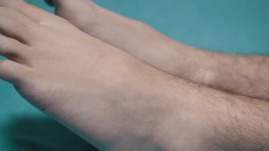 Mavi arka planda dinlenen bir adamın ayaklarının yakın çekimi. Sağlık, rahatlama ve yaşam tarzı projelerine uygundur..