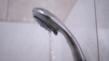 Duş başlığının kapağı fayanslı duvara su püskürtüyor. Banyo, su tesisatı ve su muhafazası için uygun..