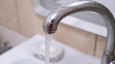 Krom banyo musluğundan sürekli akan su, su koruma ve tesisat projeleri için uygundur..
