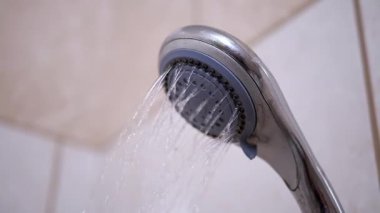 Duş başlığından fayanslı banyo duvarına doğru su akar. Banyo, hijyen ve su koruma projeleri için mükemmel..