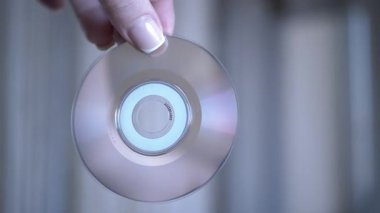 Bir el, bulanık bir arkaplan karşısında veri veya müzik kaydı için bir CD-R sunar. Teknoloji ya da nostalji teması için ideal.