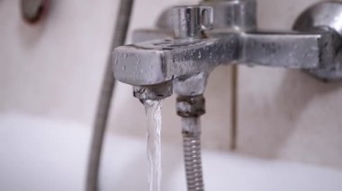 Kirli ve paslı bir banyo musluğundan akan su, bakımsız bir banyo ortamında onarıma ihtiyaç duyardı..
