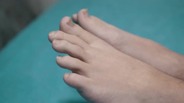 Turkuaz bir yüzeyde dinlenen çıplak ayaklı bir adamın yakın çekimi, sağlık, rahatlama ve yaşam tarzı temaları için ideal..