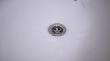 Pis, paslı bir banyo musluğundan küvete su akıyor. Armatür ve kiremitlerin durumu gerekli bakımı öneriyor.