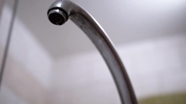 Bulanık bir zemine yavaşça damlayan bir musluk, her damlacık aşağıdan izleniyor ve şekilleniyor. Su atığını, su tesisatını ya da tamiratı görmek için mükemmel..