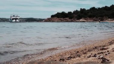 Huzurlu bir sahil sahnesinde sakin sularda dinlenen küçük bir tekne vardır. Güzel, çakıllı bir sahil şeridi.