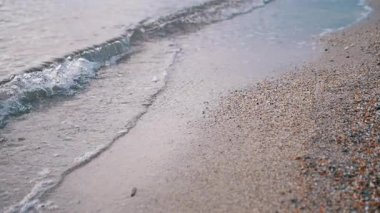 Yumuşak, yumuşak dalgalar nazikçe kumsalın kumsalındaki kumsala vuruyor. Sakin kumsal sahnesi. Yumuşak dalgalar yavaşça kumun üzerinde süzülüyor. Huzur ve sükunet hissi uyandırıyor. Yavaş çekim.