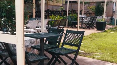 Zarif masaların ve yemyeşil yeşilliklerin serinletici bir yemek için mükemmel olduğu sakin bir açık hava yemek alanı..