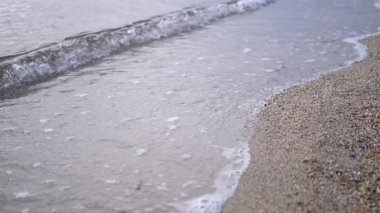 Gün batımında kumlu bir sahille ritmik olarak buluşan yumuşak dalgaların güzel sakin manzarası, derin bir rahatlama için mükemmel.