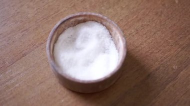 Ahşap kase ya da ahşap masa zemininde tuz dolu tuzluk. Tek bir nesne. Yemek pişirme, doğal, organik malzeme, yiyecek, sağlıklı yaşam tarzı. Ev mutfağı.