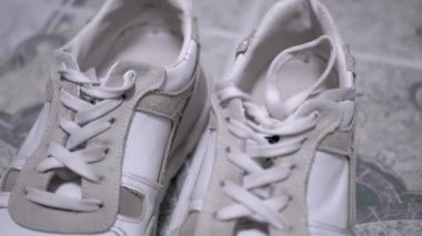 Bağcıklı beyaz spor ayakkabıları, arka planda dolar banknotları. Moda, yaşam tarzı ve finansla ilgili projeler için ideal.