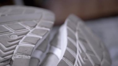 Gri bir spor ayakkabısının yıpranmış tabanlarının detaylı bir yakın çekimi, lastik izlerini ve aşınma izlerini gösteriyor. Ayakkabı, yaşam tarzı ve ürünle ilgili projeler için ideal.