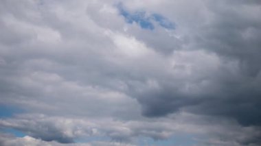 Dramatic timelapse of dark grey storm clouds gathering and moving across the sky, showing an overcast, moody atmosphere with small patches of blue visible, signaling an impending weather change.