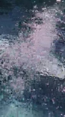 Underwater vertical perspective looking up as streams of air bubbles rise through dark, clear water, showing light from above creating shimmering effect and distorting view through liquid in a jacuzzi.