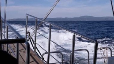 Close-up, A breathtakingly serene view from the boat, showcasing the beautiful ocean waves and intricate deck features. Texture, backgrounds. Sea voyage on a ship. Slow motion. Looped.