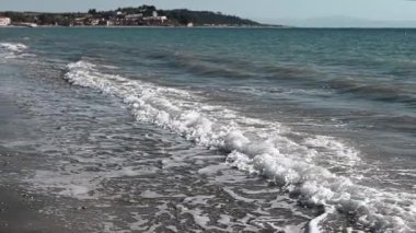 Beach sea landscape with soft waves, blue sky on the background of an island. Gentle waves softly lap against the shoreline, beautifully showcasing the tranquility of a serene coastal landscape.