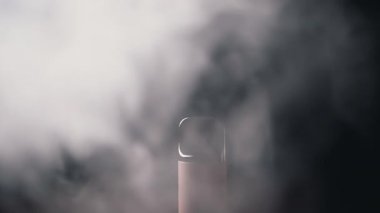 Close-up, Electronic Cigarette or Vape in Smoke on Black Background. A single slender object with emerging smoke in a dark environment, creating an enigmatic atmosphere.