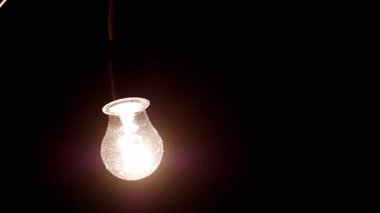 A stylish hanging light bulb illuminates a dark, moody backdrop, adding warmth and charm to the overall setting