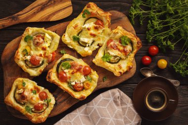 Crispy puff pastry mini tarts with zucchini, tomatoes and cheese. 