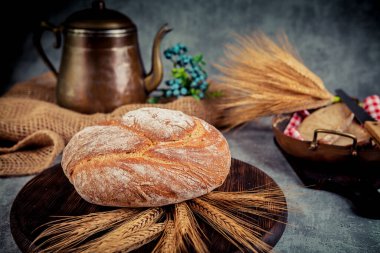 Köy arka planında taze ekmek ve buğday kulakları. Ayarlanmış.