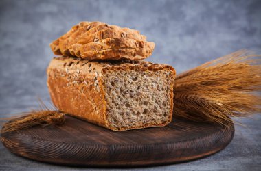 Köy arka planında taze ekmek ve buğday kulakları. Ayarlanmış.