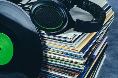 Siyah kulaklıklar bir yığın eski plağın üzerinde duruyor, yakın plan.