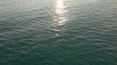 Şehir manzarasında deniz aşırı insansız hava aracının uçuş görüntüsü. Dinamik kamera eğimli çekim, ufukta gün batımı, tepeden tırnağa insansız hava aracı görüntüsü.