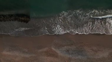 Bir dron sesi deniz ve sahile zum yapıyor. İHA mavi dalgaları ve kumları vuruyor..